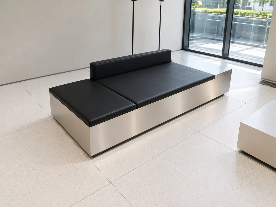 Brushed stainless steel lounge bench with black leather cushions in a business centre lobby
