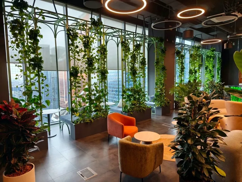Café lounge framed by green steel arches with climbing plants